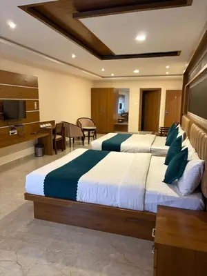 two beds in a hotel room with a television at Symphony in Ooty
