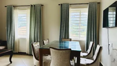 a dining room with a table and chairs at Away From Home - 4 - Rooms In Ooty, Home Stay Ooty in Ooty