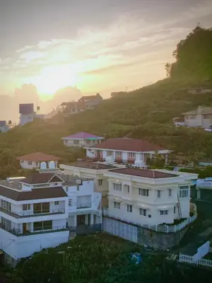 a group of white houses on a hill with the sunset at Away From Home - 4 - Rooms In Ooty, Home Stay Ooty in Ooty