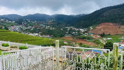 a view of a city from a white fence at Away From Home - 5 - Rooms In Ooty, Home Stay Ooty in Ooty
