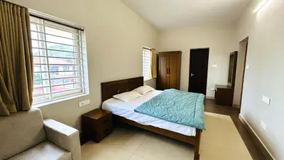 a bedroom with a bed and a window and a couch at Away From Home - 5 - Rooms In Ooty, Home Stay Ooty in Ooty