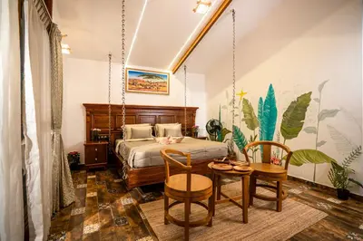 a bedroom with a bed and a table and chairs at Regenta Resort Mysore Tropical Village in Chāmundi