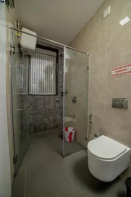 a bathroom with a toilet and a glass shower at The Haven by Xplore Indo in Ooty