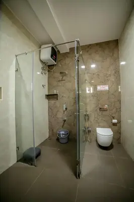 a bathroom with a shower with a toilet and a sink at The Haven by Xplore Indo in Ooty