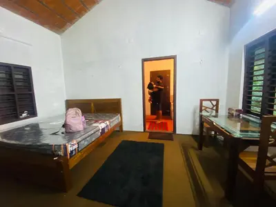 a room with a bed and a person standing in a doorway at Plantation stay in Kuttyādi