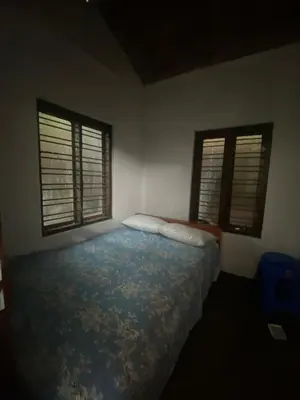 a bedroom with a bed and two windows at Plantation stay in Kuttyādi
