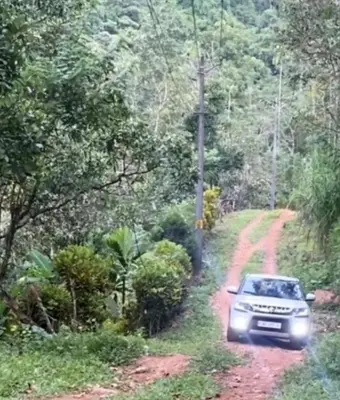 a car on a dirt road in the jungle at Plantation stay in Kuttyādi