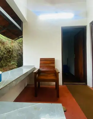 a wooden chair sitting in a room with a door at Plantation stay in Kuttyādi