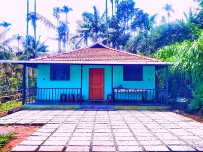 a blue house with a red door and palm trees at ADVI'S homestay in Agali
