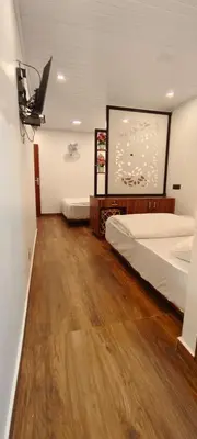 a room with two beds and a television on the wall at Birdwing Cottage, Munnar in Munnar