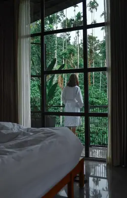 a woman looking out the window of a bedroom at Bhadra - The Estate Villa in Wayanad