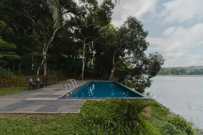 a swimming pool next to a body of water at Lakedale Resorts in Thekkumkara