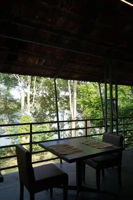 a table and chairs on a porch with a view of trees at Lakedale Resorts in Thekkumkara