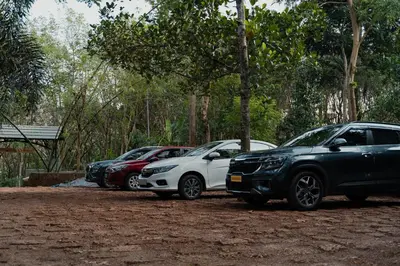 a row of parked cars parked in a dirt lot at Lakedale Resorts in Thekkumkara
