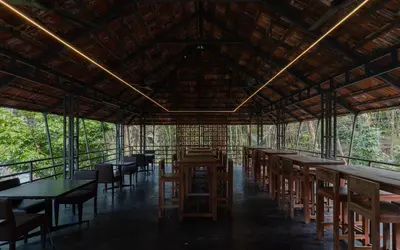 a restaurant with tables and chairs in a forest at Lakedale Resorts in Thekkumkara