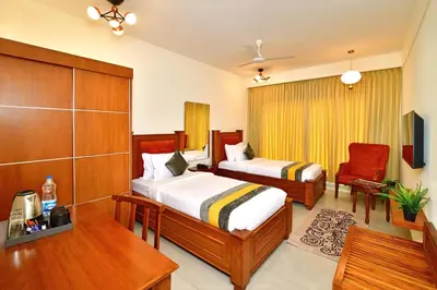 a hotel room with two beds and a chair at Eka Lyf Inn in Coimbatore
