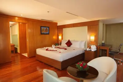 a hotel room with a bed and a table at The Garuda Hotels in Trichūr
