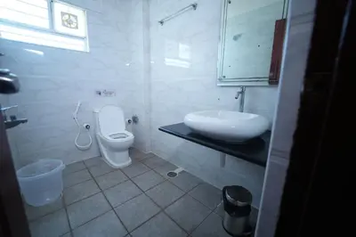 a white bathroom with a sink and a toilet at Mazus Urban Express in Mysore