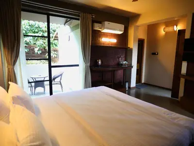 a bedroom with a bed and a table and a window at Villa Katipadu Coorg in Srimangala