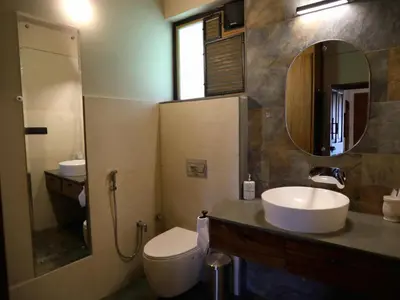 a bathroom with a sink and a toilet and a mirror at Villa Katipadu Coorg in Srimangala