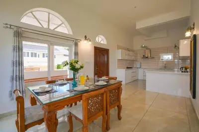 a large kitchen with a table and a large window at Emerald Stays Ooty By VOYE HOMES - Italian Luxury near Ooty Emerald Lake in Ooty