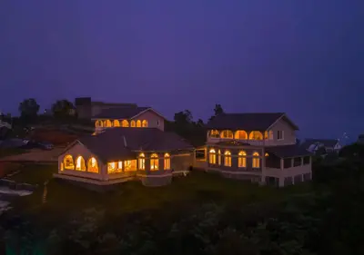 a large house with lights on it at night at Emerald Stays Ooty By VOYE HOMES - Italian Luxury near Ooty Emerald Lake in Ooty