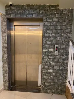 a elevator in a building with a stone wall at moona apartments in Malappuram