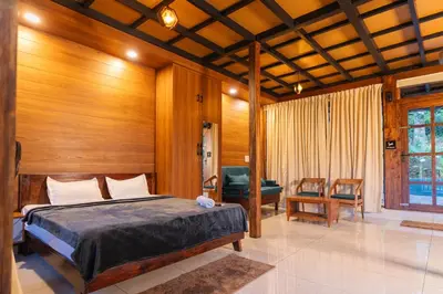 a bedroom with a bed in a room with wooden walls at Ethnic Villa Wayanad in Kenichira