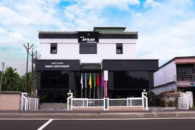 a white building with flags in front of it at Hotel Afrad International in Kondotti