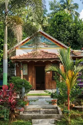 a house with a palm tree in front of it at Birds Island Ayur-Yoga Retreat in Ernakulam