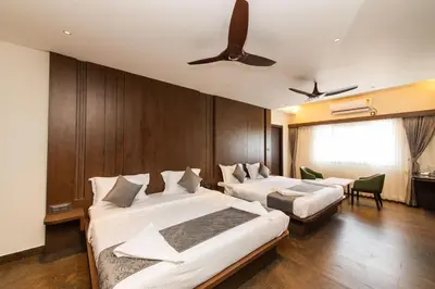 a hotel room with two beds and a ceiling fan at Hotel Mysore Radiance in Mysore