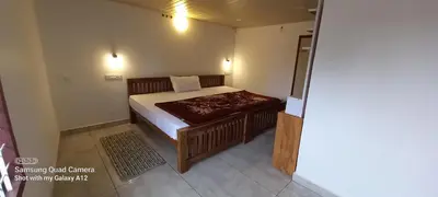 a small bedroom with a bed and a table at Perumaal Homestay in Munnar