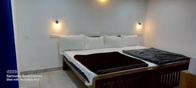 a bedroom with a large bed with white walls at Perumaal Homestay in Munnar