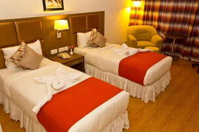 a hotel room with two beds and a chair at The Atrium Boutique Hotel in Mysore