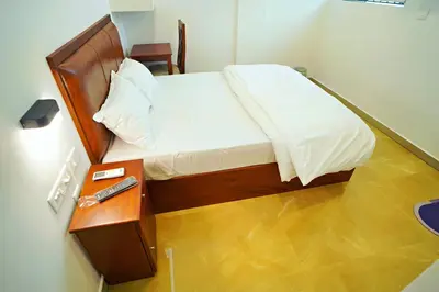 a bed in a room with a night stand with a remote control at GH Grand Park in Angamali