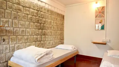 a room with two beds and a brick wall at Roambay - Gokulam in Mysore