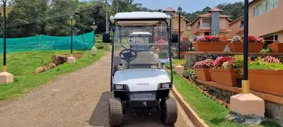 a golf cart driving down a dirt road at Royal Crown resorts in Kotagiri