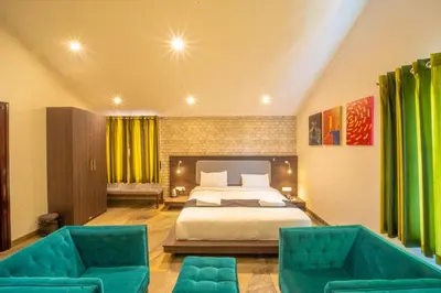 a bedroom with a bed and two green chairs at Royal Crown resorts in Kotagiri