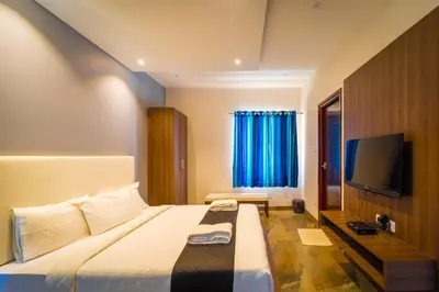a hotel room with a bed and a flat screen tv at Royal Crown resorts in Kotagiri