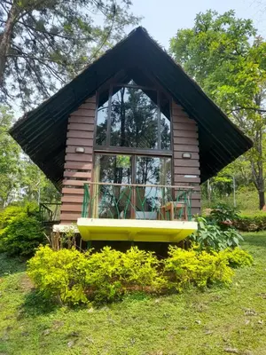 a small house with a large window in the grass at Gorukana Eco Wellness Centre in Honganūr