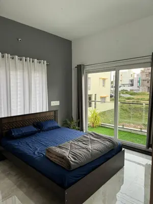 a bedroom with a bed and a large window at Stayover Homestay in Mysore