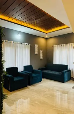 a living room with two blue couches and curtains at Stayover Homestay in Mysore
