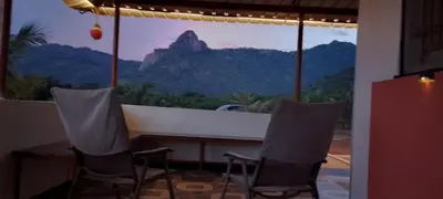 a room with chairs and a large window with a mountain view at Beyond Ghatts Homestay in Dhali