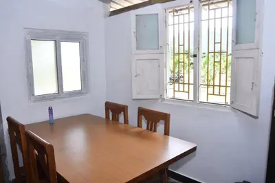 a dining room with a wooden table and two windows at Beyond Ghatts Homestay in Dhali