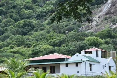 a white house with a mountain in the background at Beyond Ghatts Homestay in Dhali