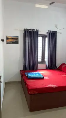 a bedroom with a red bed with a window at Scott legacy apartment in Kulattūr