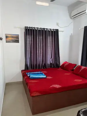 a bedroom with a red bed with black curtains at Scott legacy in Kulattūr