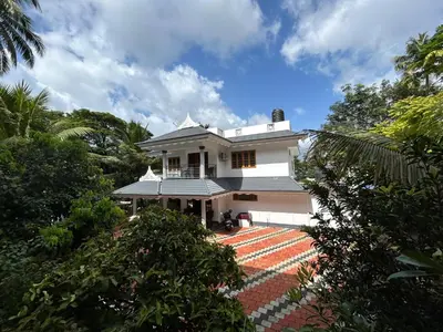 a white house in the middle of trees at Puzhayoram Homestay in Trichūr