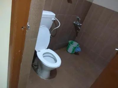a bathroom with a white toilet in a stall at Gerones Residency Serviced Apartments & Home Stays in Coimbatore