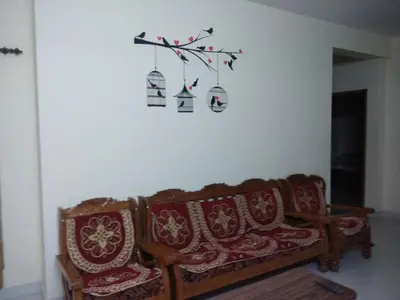 a living room with two couches and a bird cage on the wall at Gerones Residency Serviced Apartments & Home Stays in Coimbatore